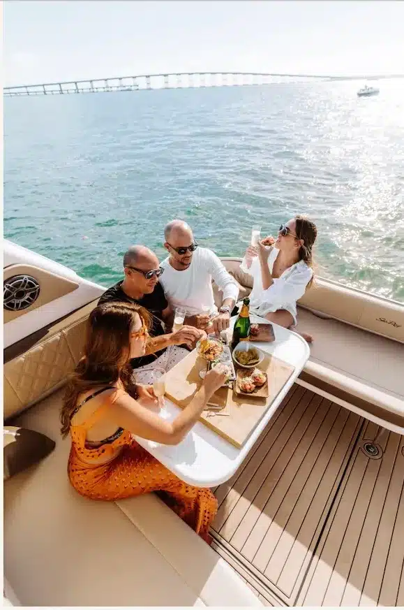 Guests dining and celebrating on the stern of the 40 Sea Ray yacht on a sunny day in Miami with champagne and food