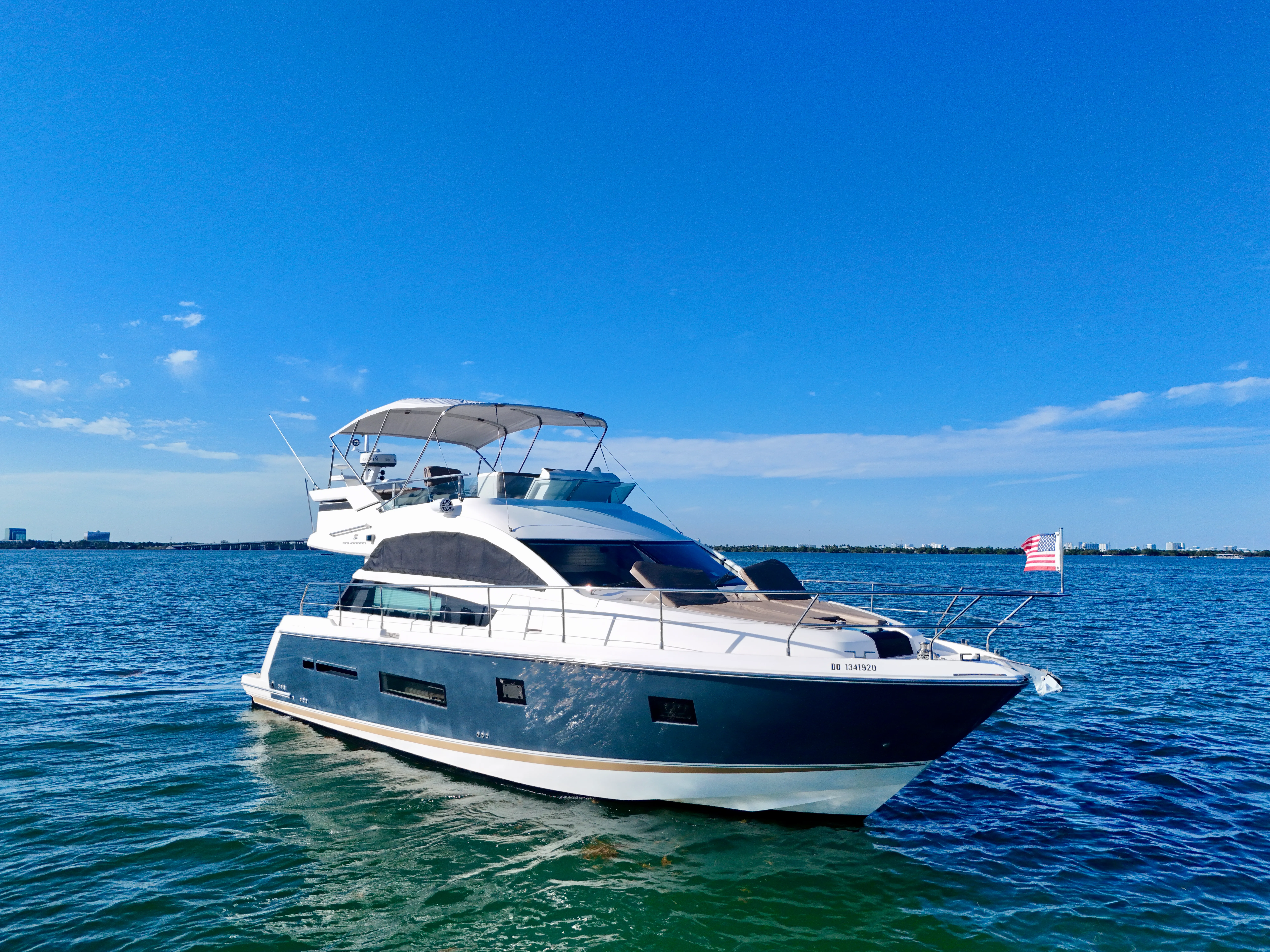 46 Flybridge sport yacht side profile on Miami water — private charter with downtown skyline