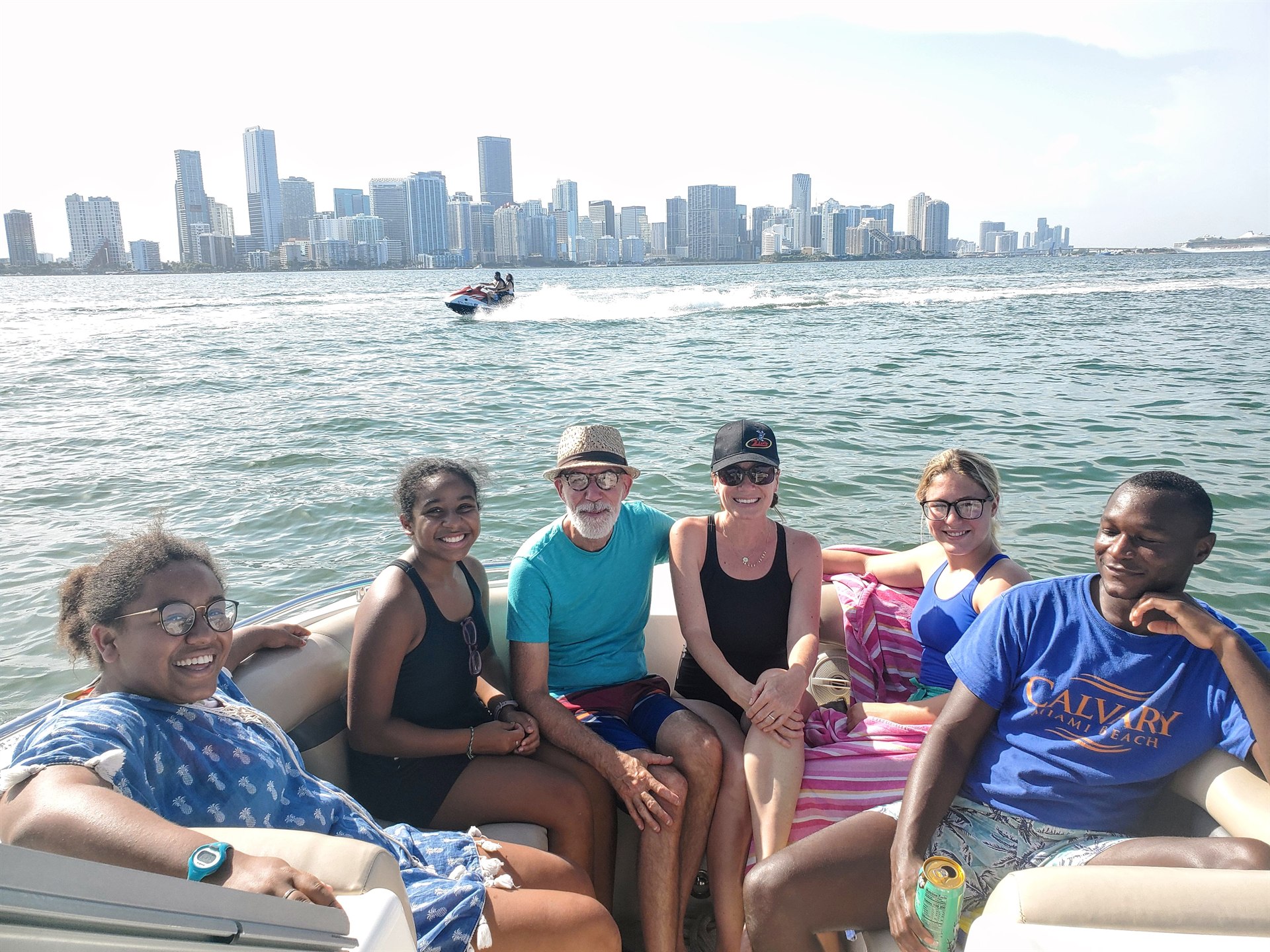 Family group on a private Miami boat with the skyline and a passing jet ski on Biscayne Bay