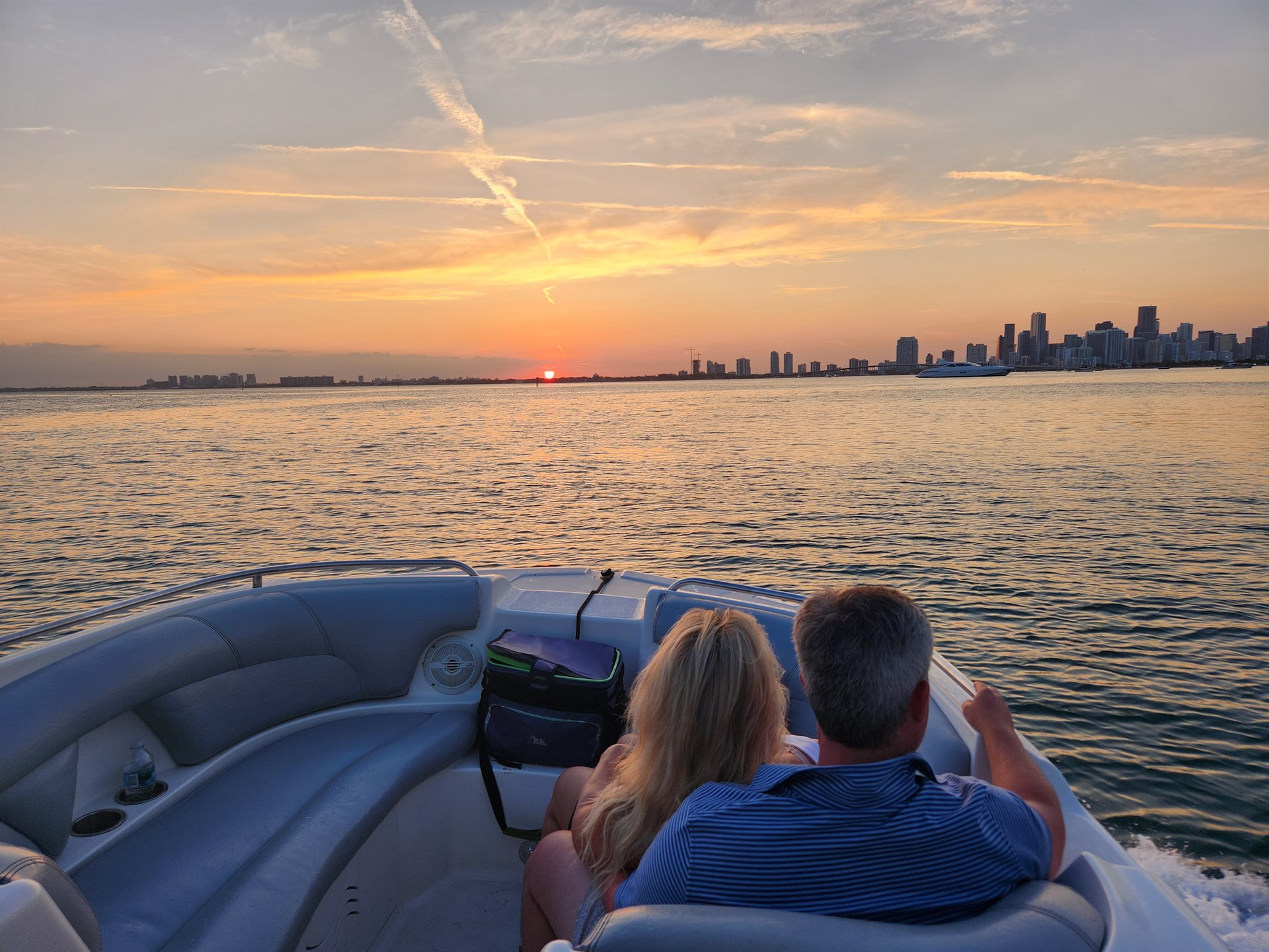 Couple on the bow of a private Miami boat watching sunset over the Biscayne Bay skyline