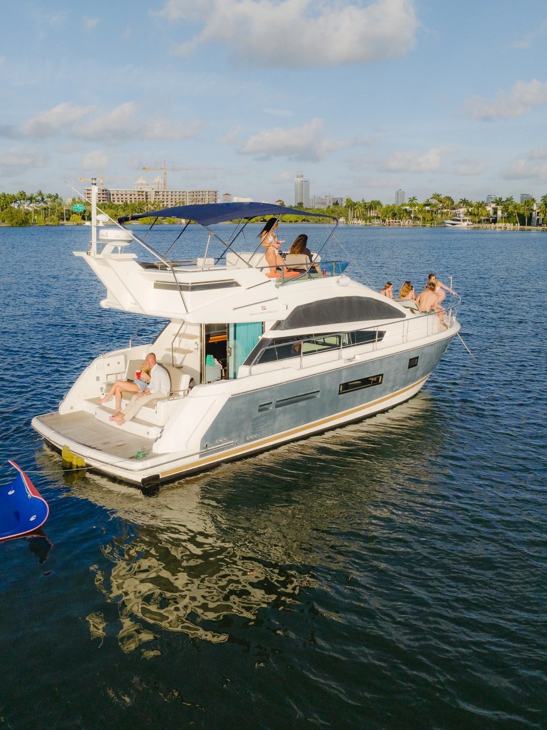 Guests on the 46 Flybridge flybridge and swim platform with a floating mat alongside