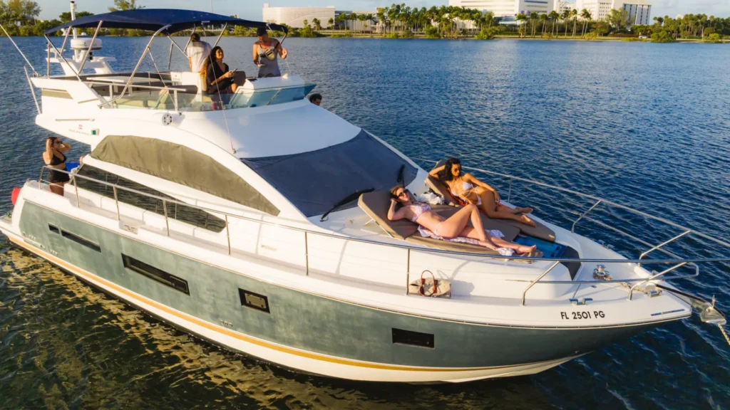Aerial view of a private motor yacht cruising Biscayne Bay in Miami with guests on the bow at golden hour