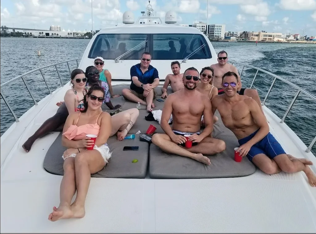 Mixed group of friends relaxing on the bow sun pad of a yacht cruising past the Miami skyline