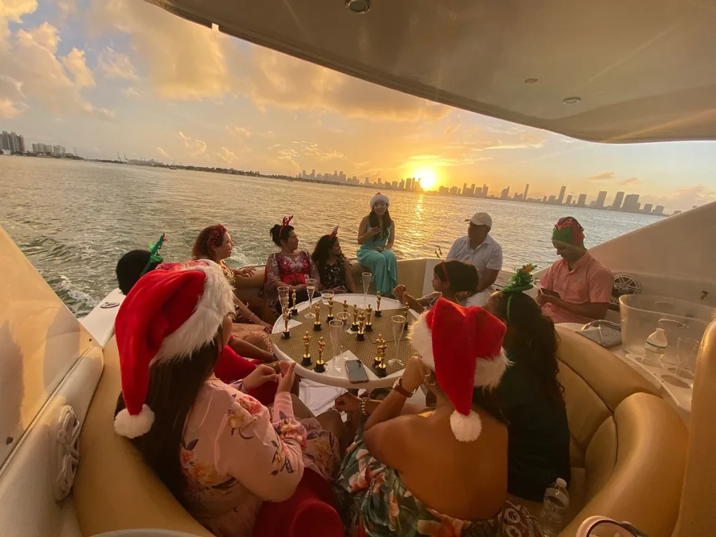 Guests in Santa hats celebrating a holiday party on a yacht as the sun sets over the Miami skyline
