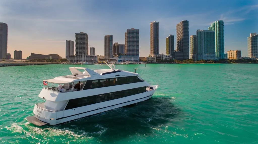 Aerial view of the 100′ Midnight Sun yacht cruising Biscayne Bay with the Miami skyline behind