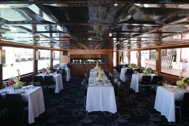 Main dining room of the 100′ Midnight Sun yacht set with white-linen tables for a corporate dinner